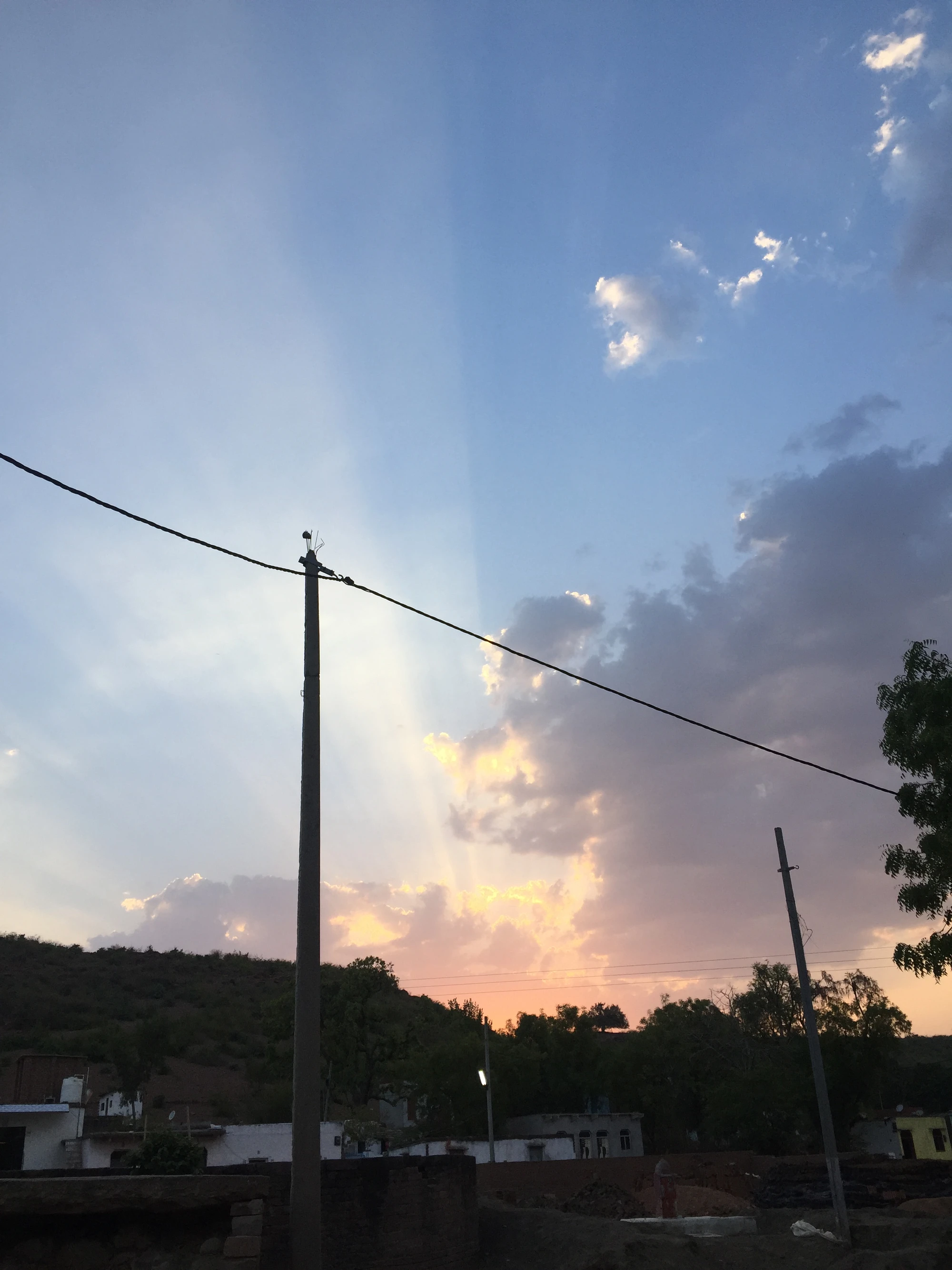 The sun setting over hills and a lake, seen through a wooden railing