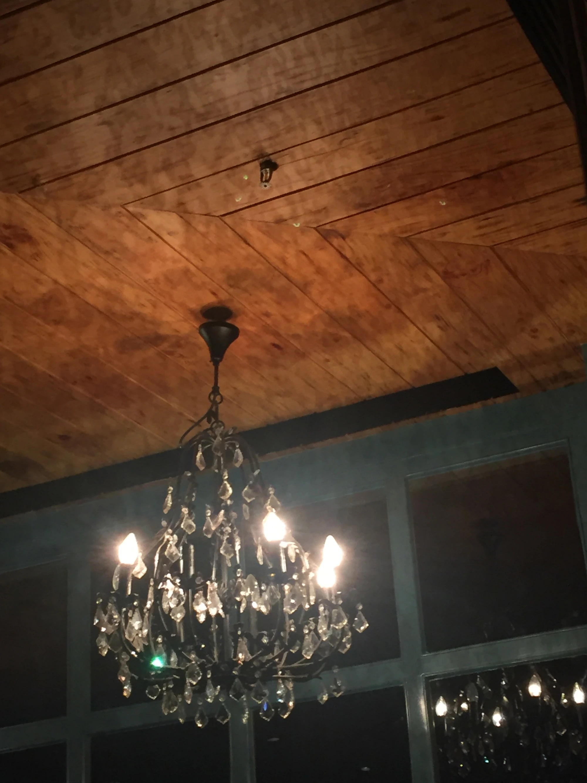 An ornate crystal chandelier hanging from a wood-paneled ceiling