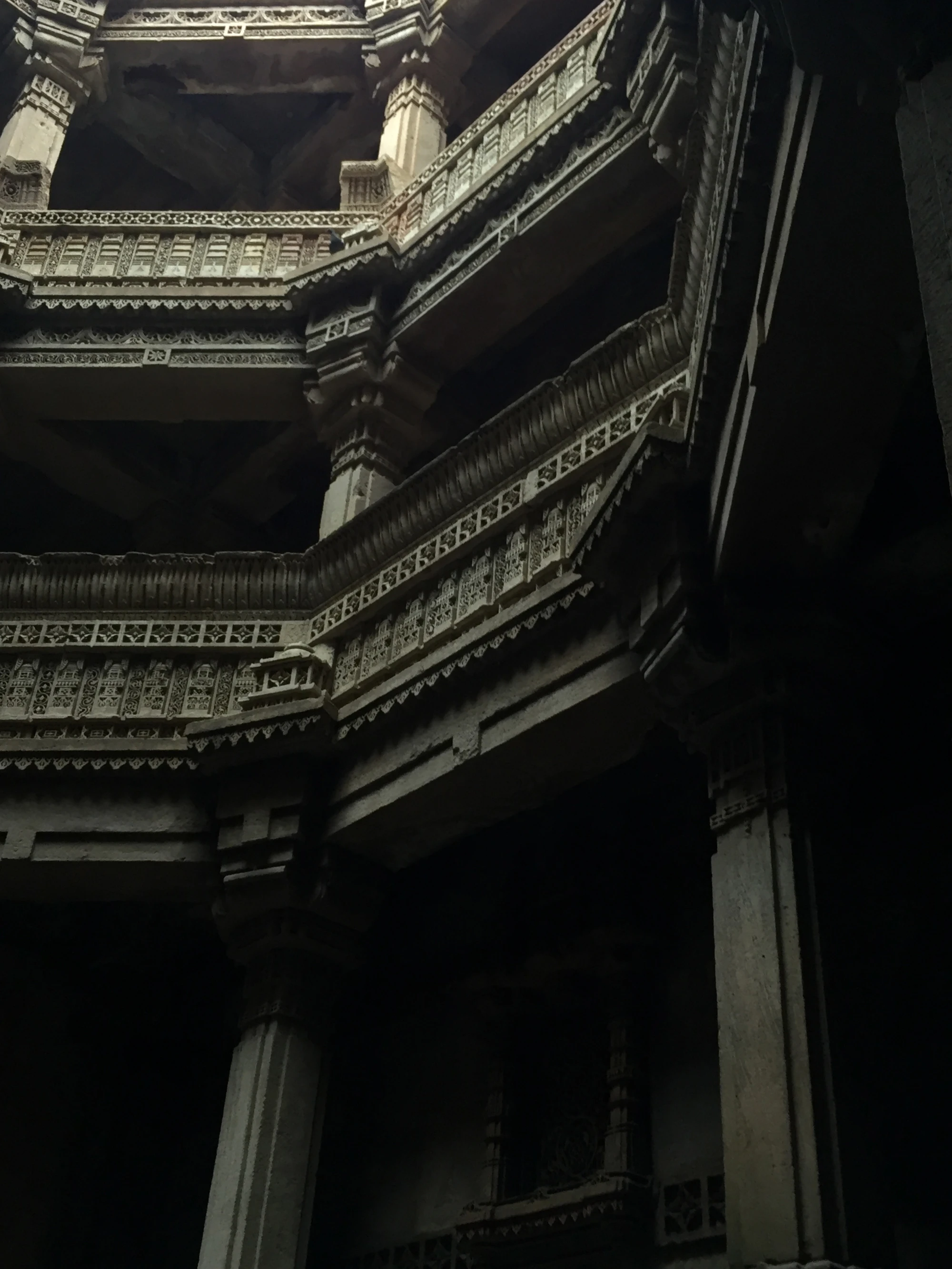 A stepwell balcony carved in stone, lit by dramatic side light