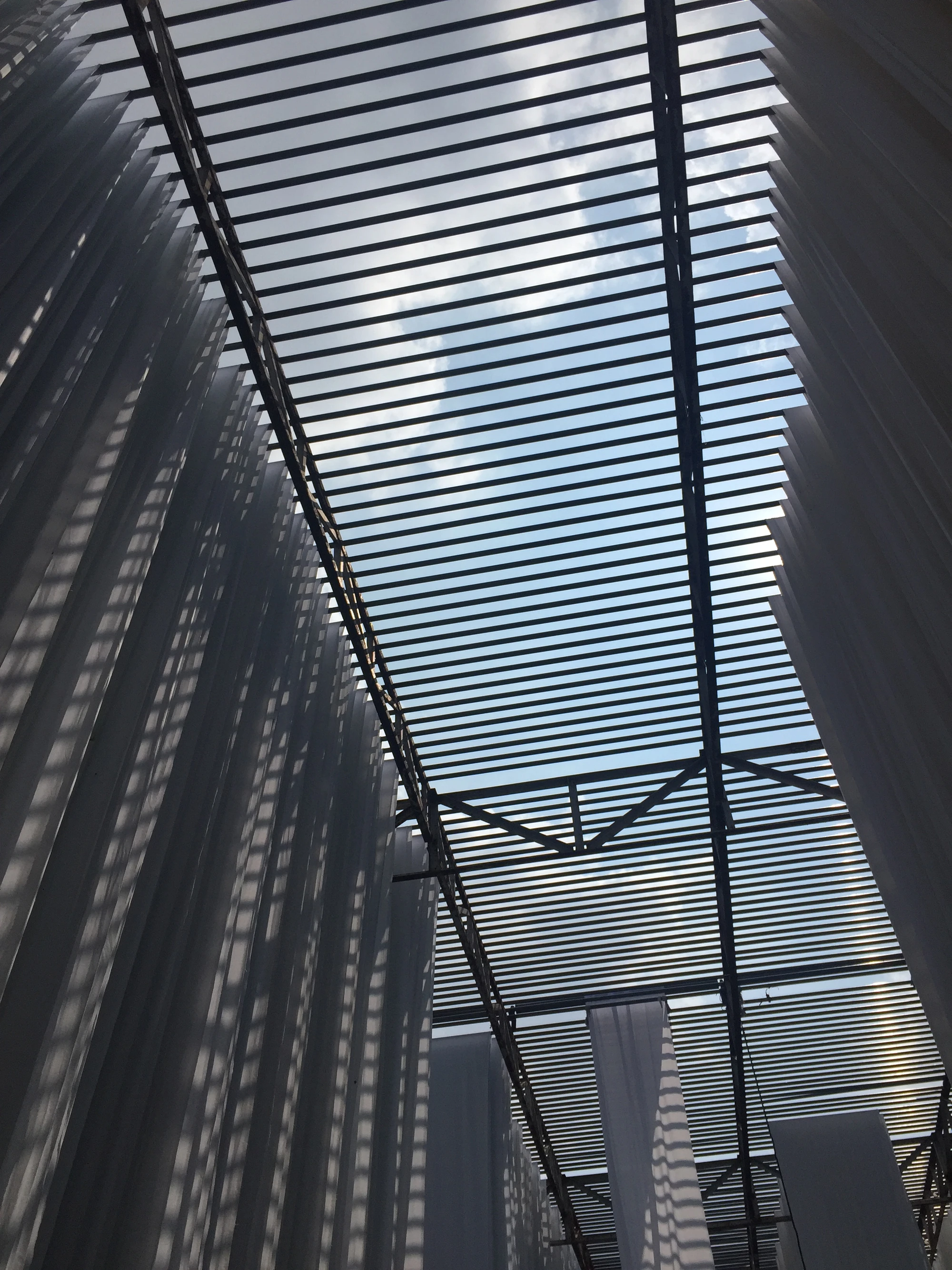 White fabric drying under a corrugated metal roof against the sky