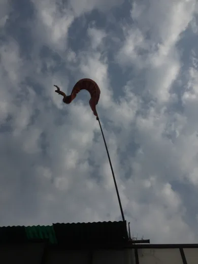 An orange flag curling in the wind against a cloudy sky