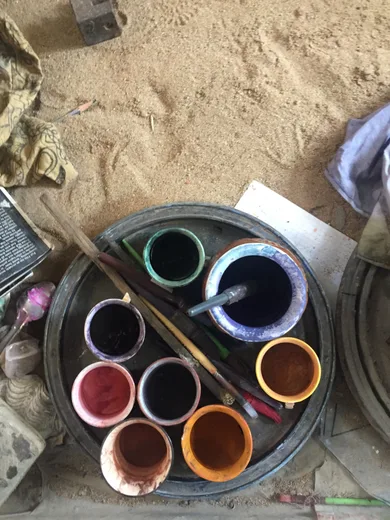 An overhead view of paint bowls, brushes, and pigment trays