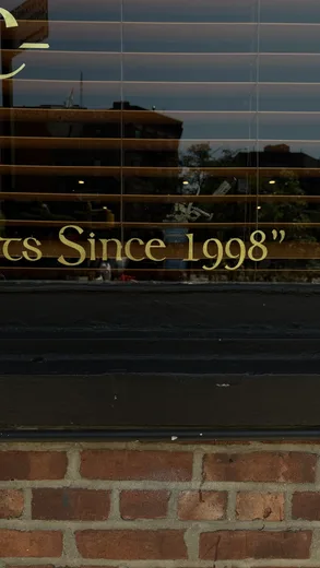 A shop window sign reading "Since 1998" over a brick wall