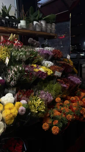 A flower stall with yellow, orange and white blooms