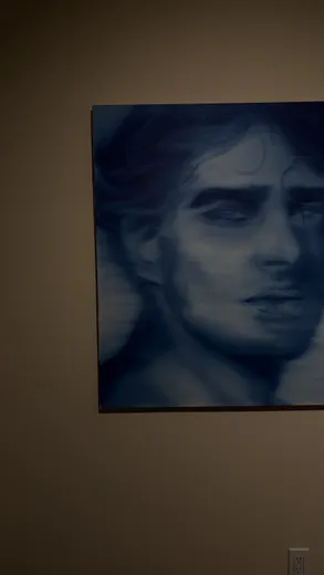 A blue portrait painting on a dark wall