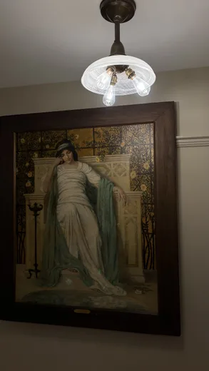 A framed painting of a robed figure under a lamp