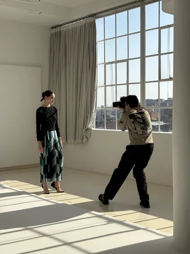 A person photographing another in a sunlit white room