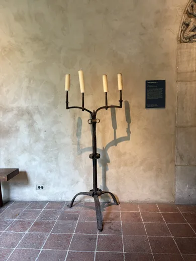 A candelabra on a stone floor against a plaster wall